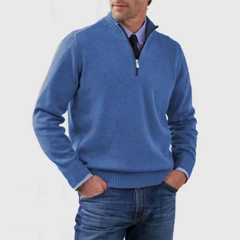 Homme portant un pull bleu à col zippé, manches longues, sur une chemise bleue et un jean. Mode masculine élégante et décontractée.