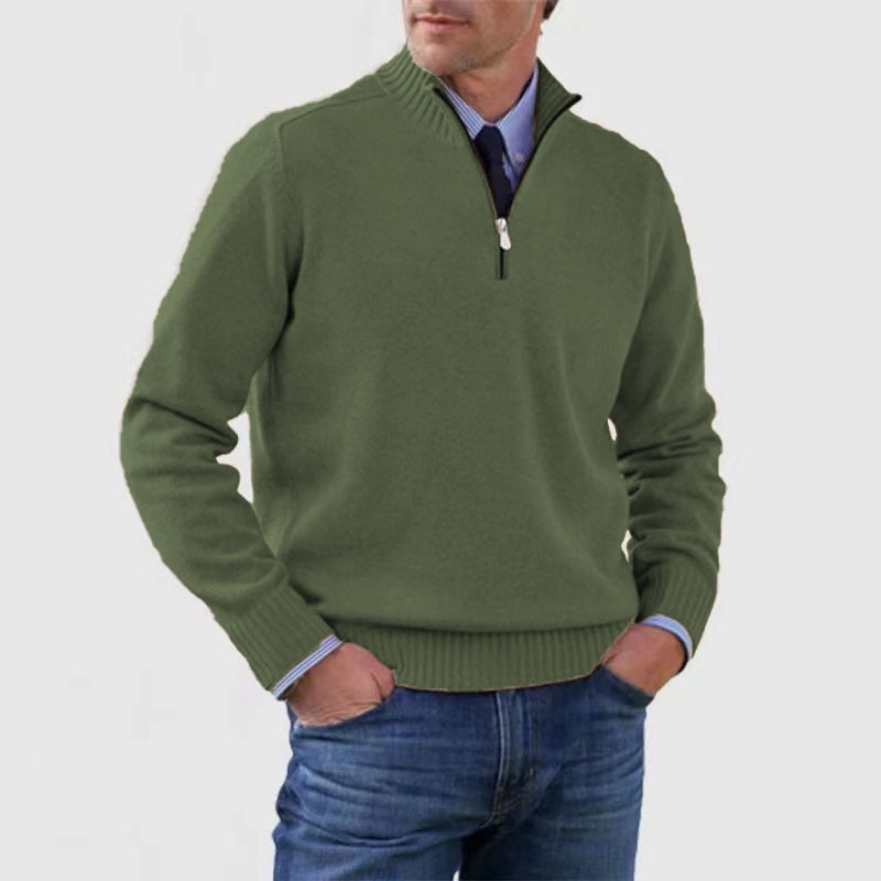Homme portant un pull vert à col zippé, manches longues, sur une chemise bleue, avec un jean bleu. Mode masculine décontractée et élégante.