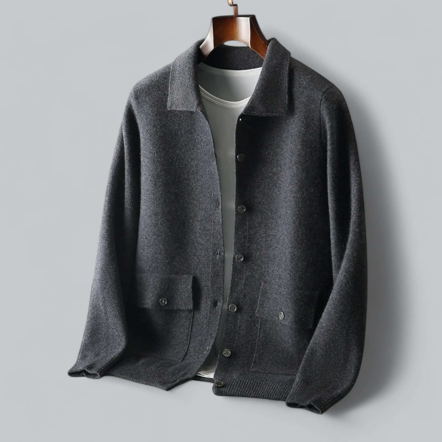 Cardigan en laine gris foncé pour homme, avec col classique et boutons, suspendu sur cintre. Mode masculine élégante, vêtement automne-hiver.