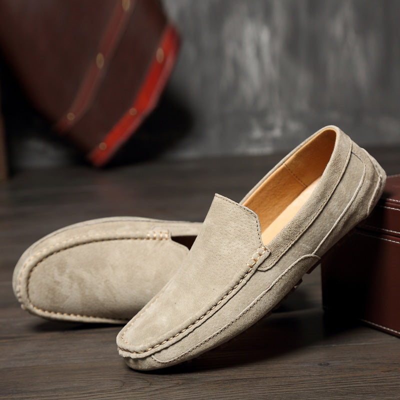 Mocassins en daim beige pour homme posés sur un sol en bois, style décontracté et élégant, parfaits pour la mode masculine et le confort quotidien.