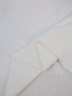 Pull en laine blanc texturé, gros plan sur les détails des mailles et des bords côtelés, style élégant et minimaliste.