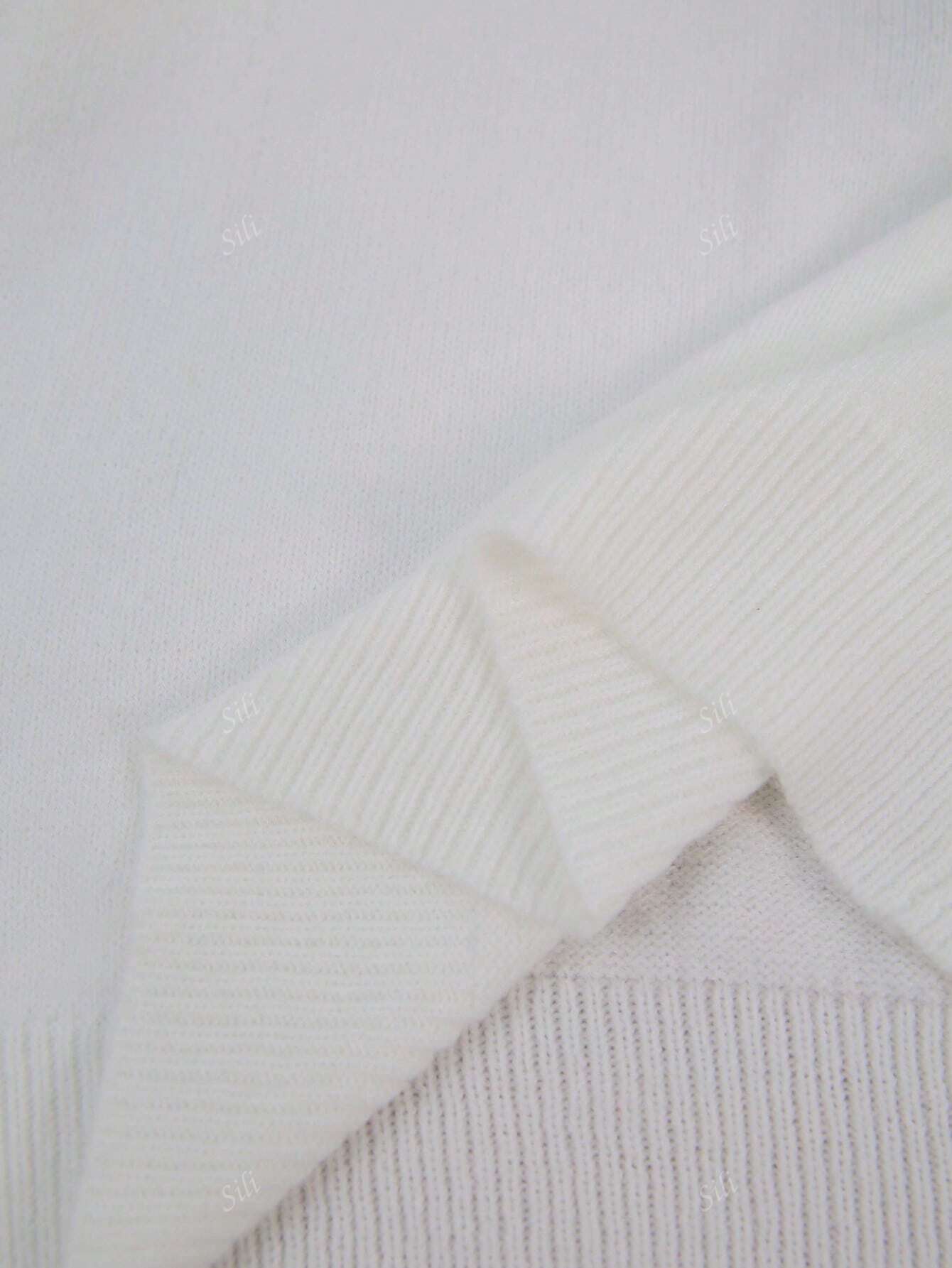 Pull en laine blanc texturé, gros plan sur les détails des mailles et des bords côtelés, style élégant et minimaliste.