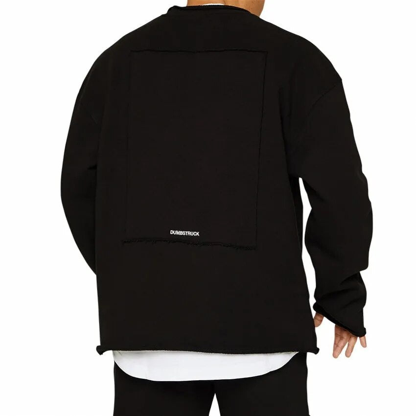 Homme portant un sweat-shirt noir oversize avec un design minimaliste, marque Dumbstruck visible, style urbain moderne.
