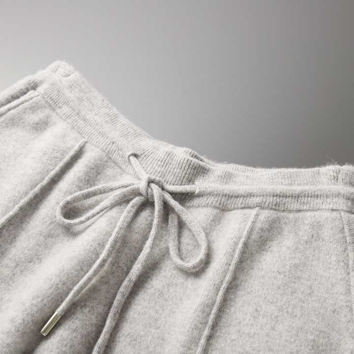 Pantalon de jogging gris en laine avec cordon de serrage, style décontracté, mode automne-hiver, confort et élégance, gros plan sur la texture.