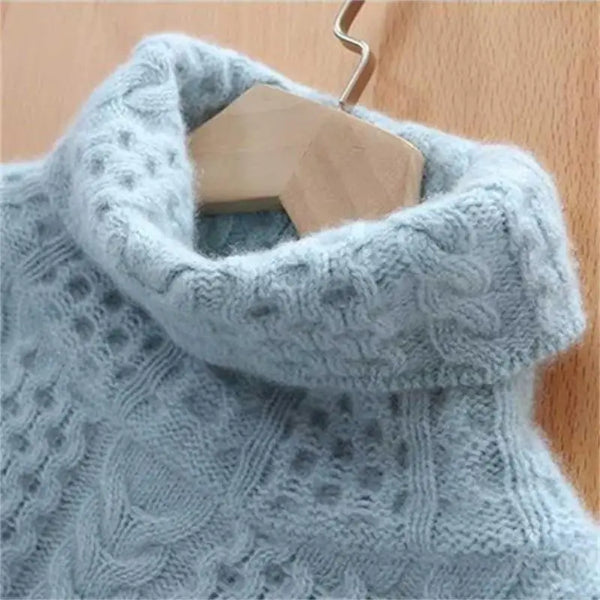 Pull en laine bleu clair avec col roulé torsadé, suspendu sur un cintre en bois. Tricot texturé, mode hiver, vêtement chaud et confortable.