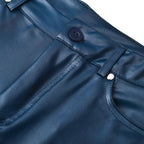 Pantalon en satin bleu marine avec bouton noir et rivets argentés, tissu brillant, mode élégante, gros plan sur la ceinture et la poche avant.