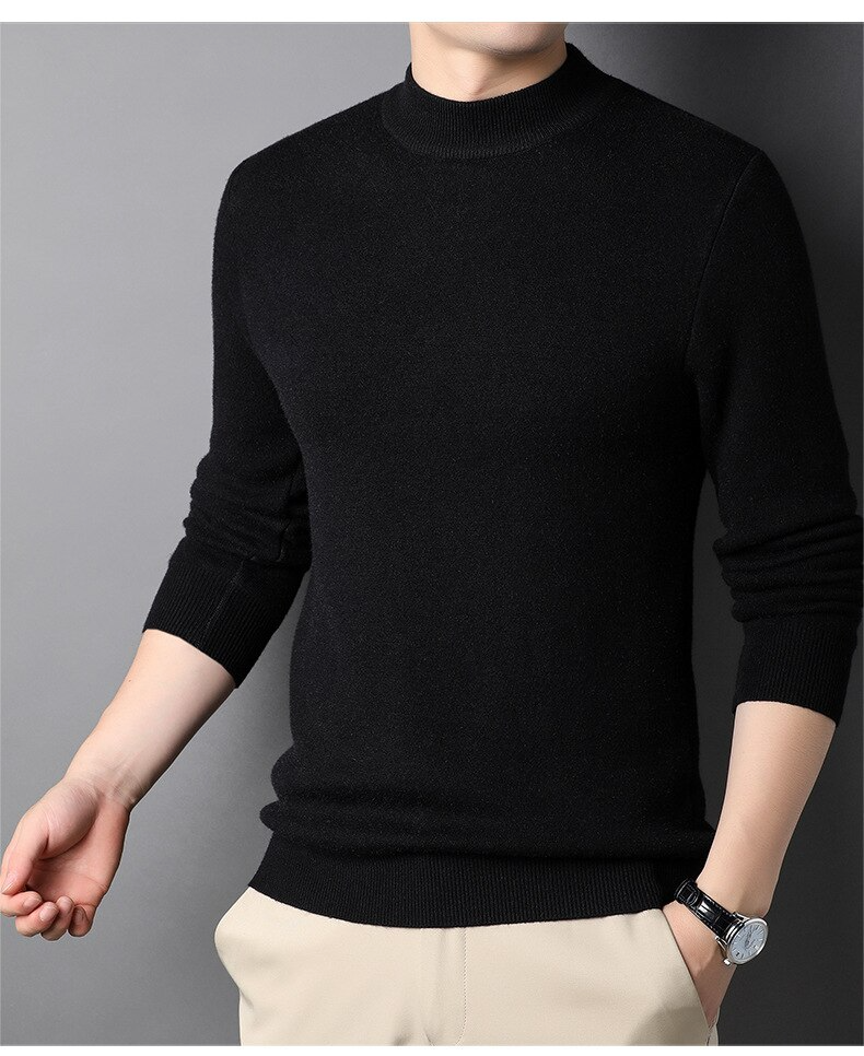 Homme portant un pull noir à col rond, manches longues, avec pantalon beige. Mode masculine élégante, tenue automne-hiver, style décontracté.