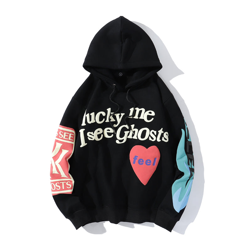 Sweat à capuche noir "Lucky Me I See Ghosts" avec motifs colorés, cœur rouge et texte sur les manches. Mode streetwear tendance, style urbain.