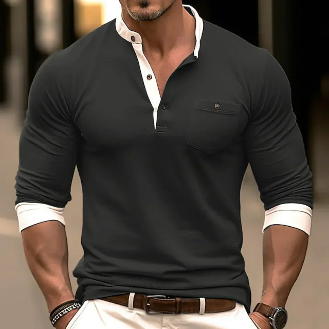 Homme musclé portant un polo noir élégant avec col blanc, manches retroussées, et pantalon blanc. Mode masculine, style chic et moderne.