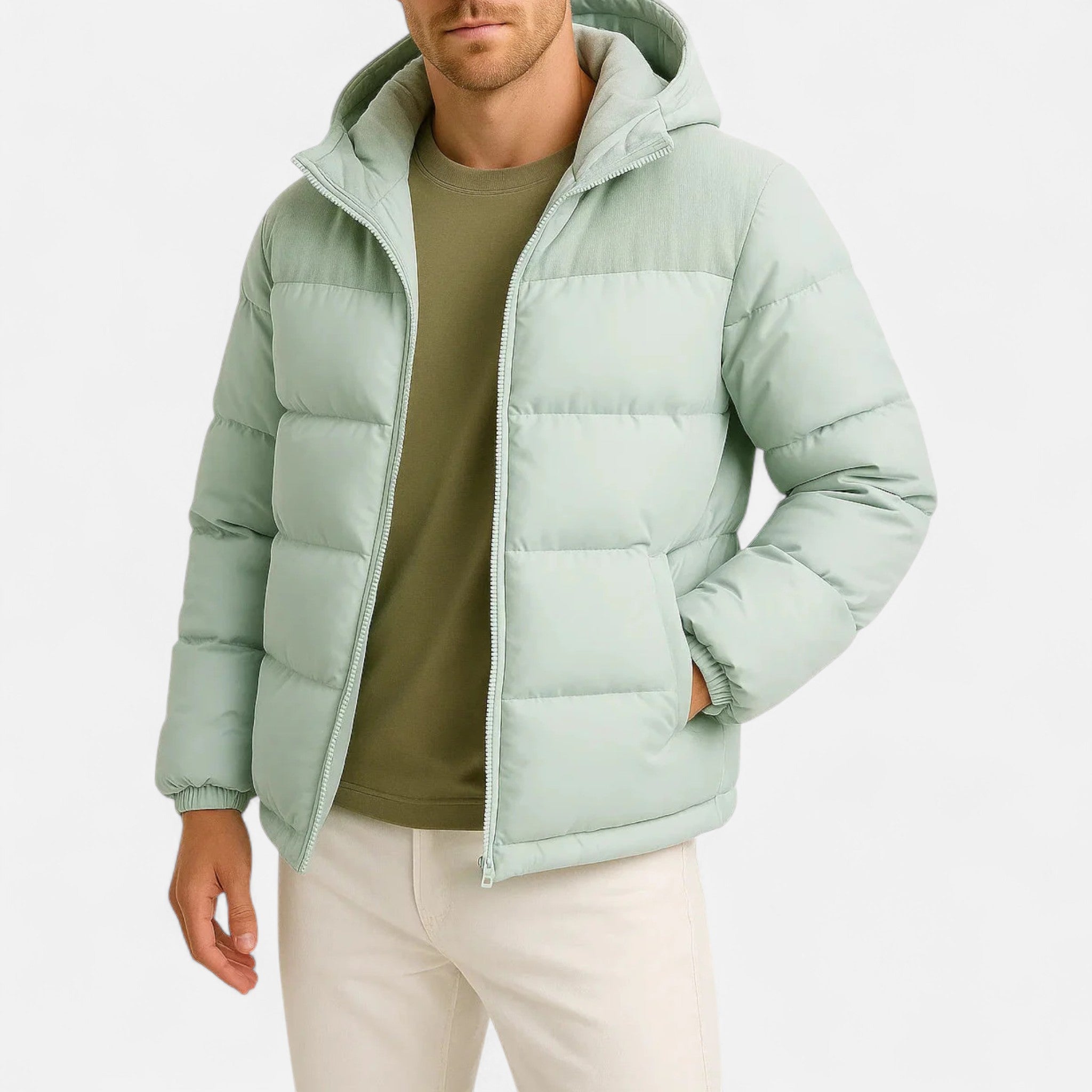 Homme portant une doudoune verte avec capuche, t-shirt vert olive et pantalon beige. Mode hiver, veste matelassée, tenue décontractée.