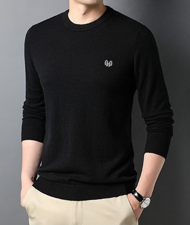 Homme portant un pull noir élégant, manches longues, avec logo discret, sur fond gris. Mode masculine, style décontracté chic, automne-hiver.