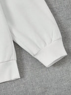 Manche de sweat-shirt blanc en coton sur fond gris, mode décontractée, vêtement confortable, style minimaliste, tendance automne-hiver.