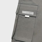 Poche de pantalon cargo gris avec rabat et étiquette "Collection", style utilitaire moderne, mode urbaine tendance, tissu résistant.