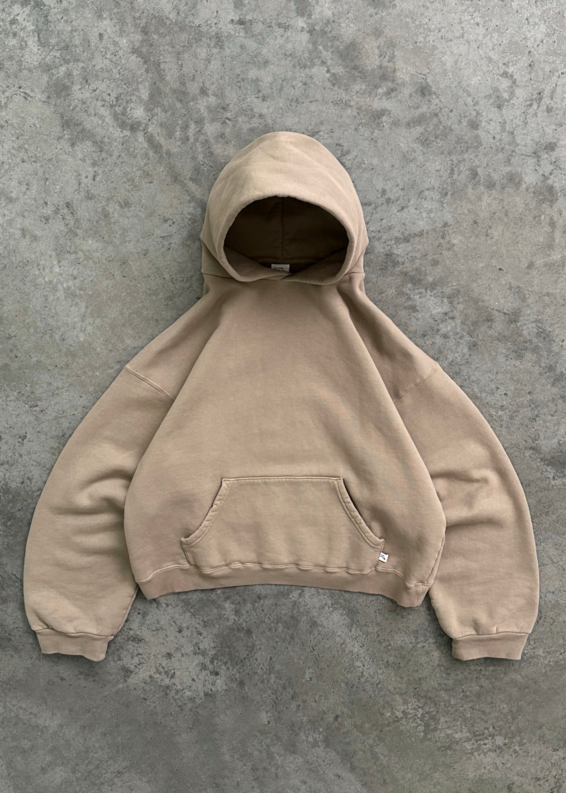 Sweat à capuche beige sur fond gris, style décontracté, poche kangourou, manches longues, tendance mode urbaine, vêtement unisexe confortable.
