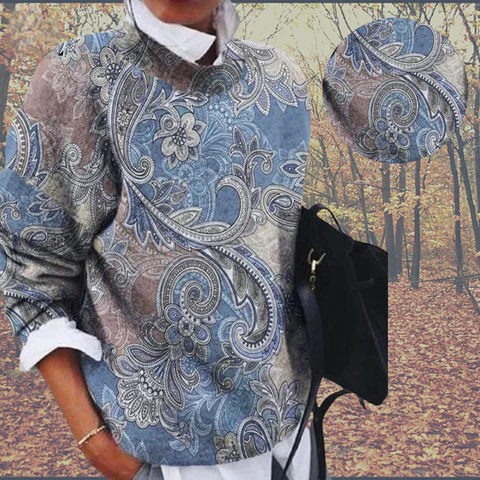 Pull-over à motifs cachemire bleu et beige, manches longues, porté par une personne dans un parc automnal. Accessoire: sac noir. Mode automne.