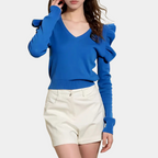 Femme portant un pull bleu à manches longues avec volants et un short blanc. Mode féminine élégante, tenue décontractée chic.