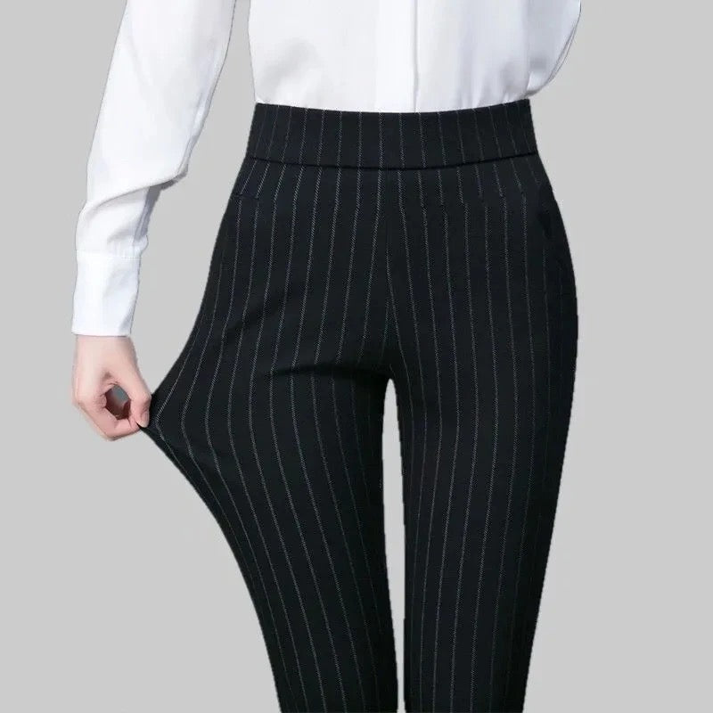 Pantalon noir à rayures verticales, ajusté et élégant, porté avec une chemise blanche. Mode femme, tenue professionnelle chic.