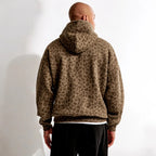 Homme portant un sweat à capuche imprimé léopard marron, vu de dos, sur fond blanc. Mode urbaine, tendance automne, style décontracté.