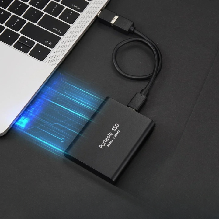 Disque SSD portable connecté à un ordinateur portable via un câble USB, illustrant la vitesse de transfert de données avec des effets lumineux bleus.