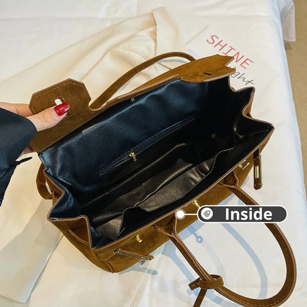 Sac à main en cuir marron ouvert, intérieur noir, sur un lit blanc. Mode féminine, accessoire tendance, élégance, style chic.