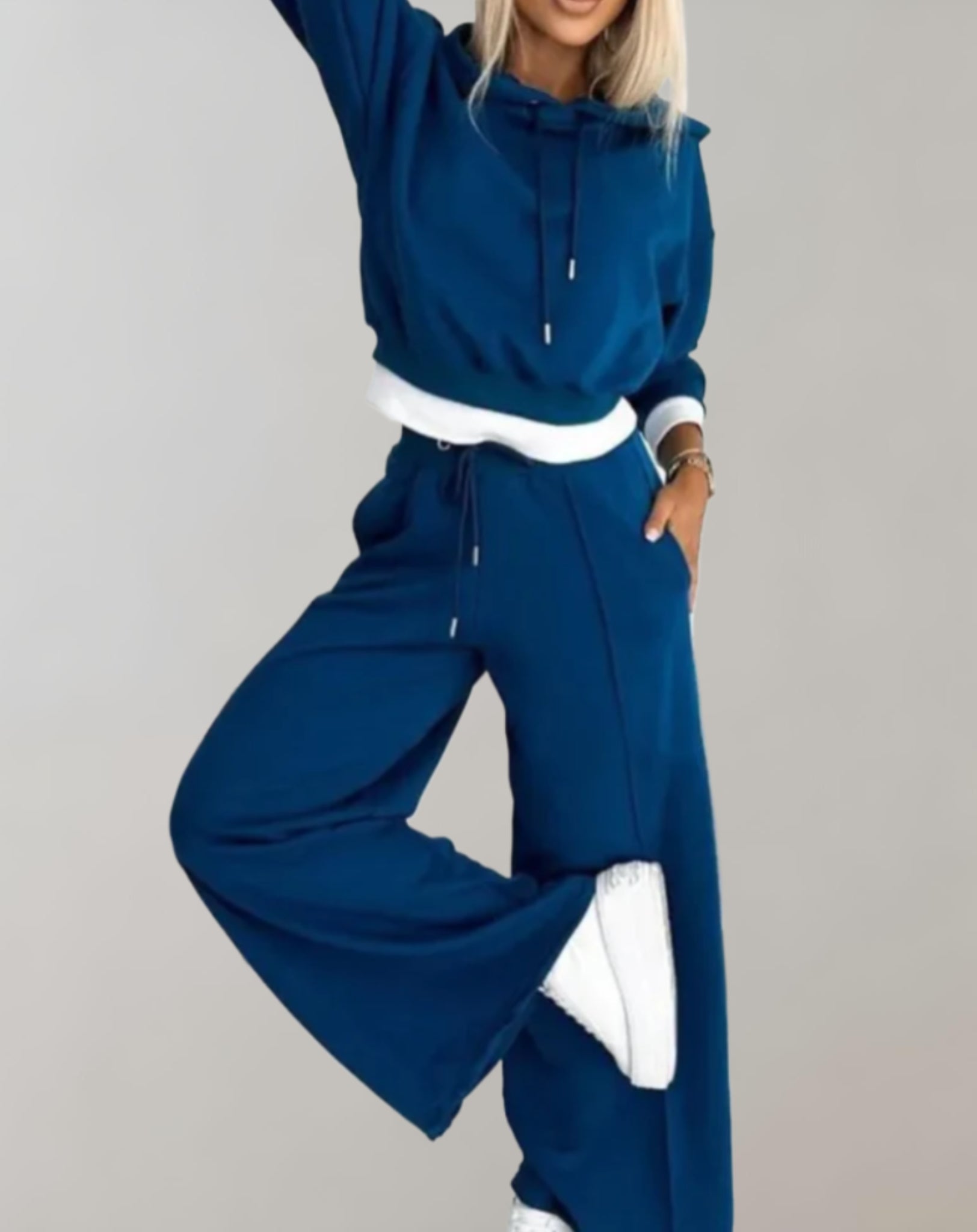 Femme en survêtement bleu marine, posant avec style. Tenue décontractée, mode féminine, confort, tendance automne-hiver, baskets blanches.