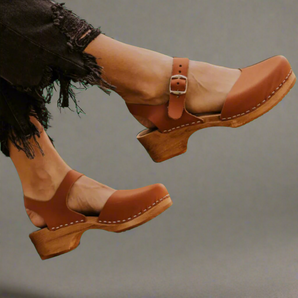 Chaussures en cuir marron avec talons en bois, style sabots, portées avec un jean noir effiloché. Mode rétro, tendance chaussures femme.