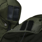 Gros plan sur une veste verte avec fermeture éclair et attaches Velcro noires, idéale pour l'hiver. Vêtement chaud et résistant pour temps froid.