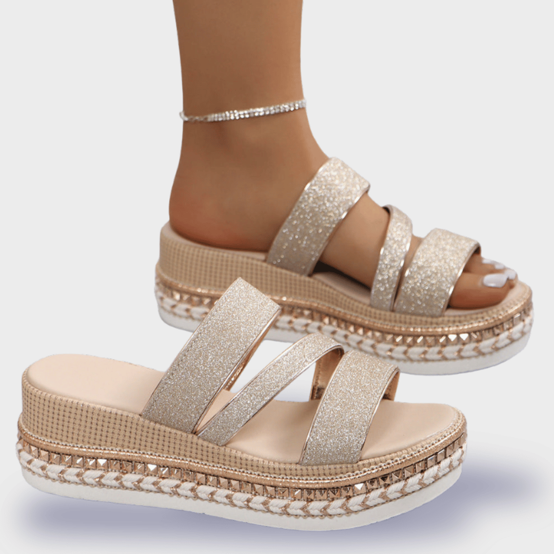 Sandales compensées dorées à paillettes avec trois brides, semelle tressée et cheville ornée d'un bracelet. Mode estivale élégante et tendance.
