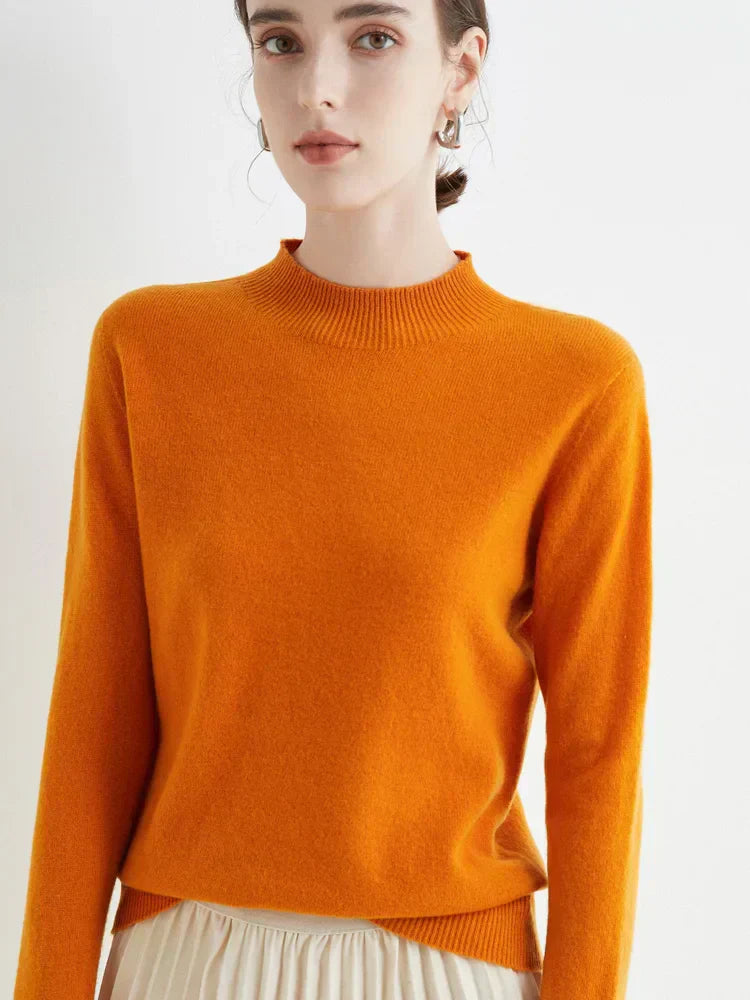 Jeune femme portant un pull orange vif en laine, manches longues, col rond, posant contre un fond blanc. Mode automne, style élégant et moderne.