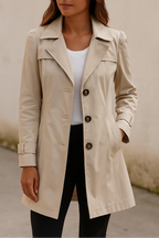 Femme portant un trench-coat beige élégant, manches longues, boutons marron, sur un fond neutre. Mode automne, manteau classique, style chic.