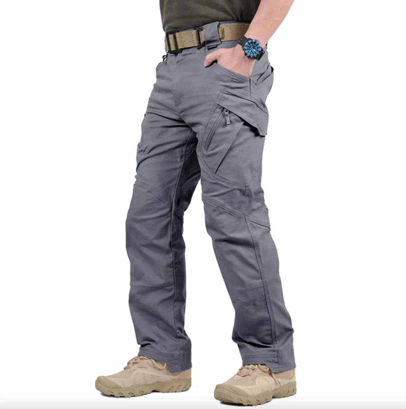 Pantalon tactique gris pour homme, poches multiples, ceinture ajustée, chaussures de randonnée beige, montre bleue, style outdoor robuste.