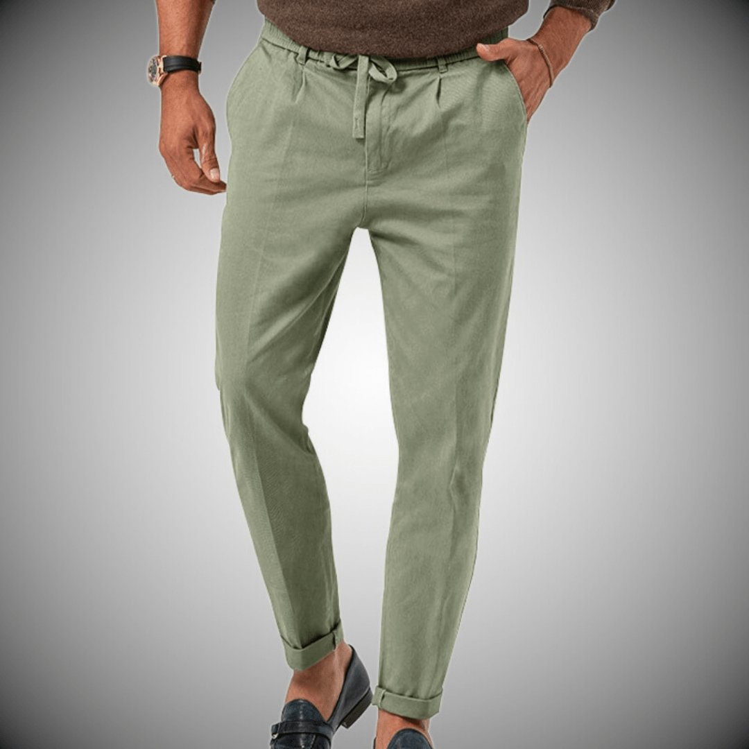 Pantalon vert olive pour homme, coupe décontractée, avec ceinture à cordon, porté avec un pull marron et des mocassins noirs. Mode masculine élégante.