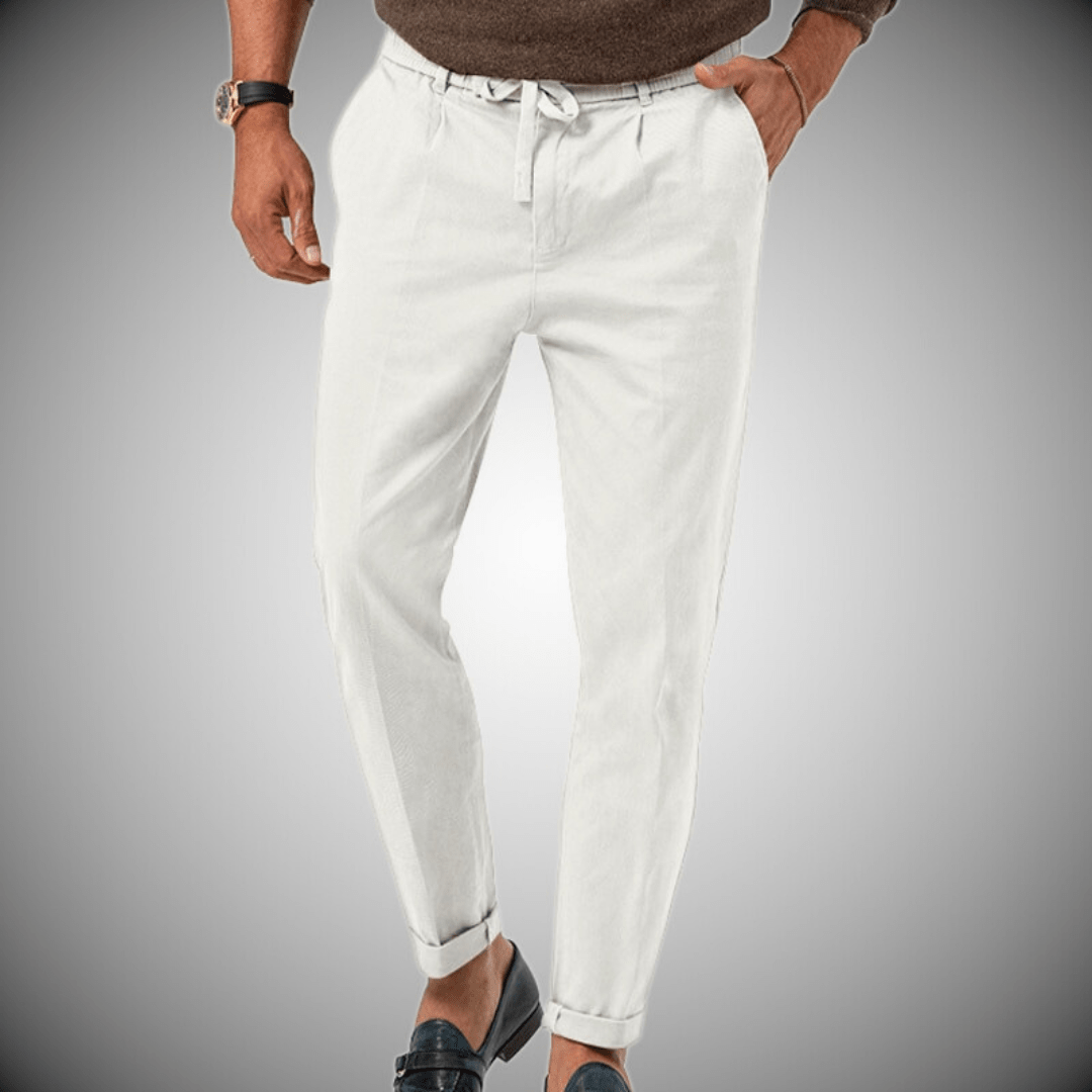 Pantalon blanc homme élégant, coupe décontractée, ceinture à cordon, poches latérales, porté avec mocassins noirs et pull marron.