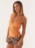 Jeune femme portant un haut orange perlé et un short imprimé léopard, posant sur fond blanc. Mode féminine, tenue estivale tendance.