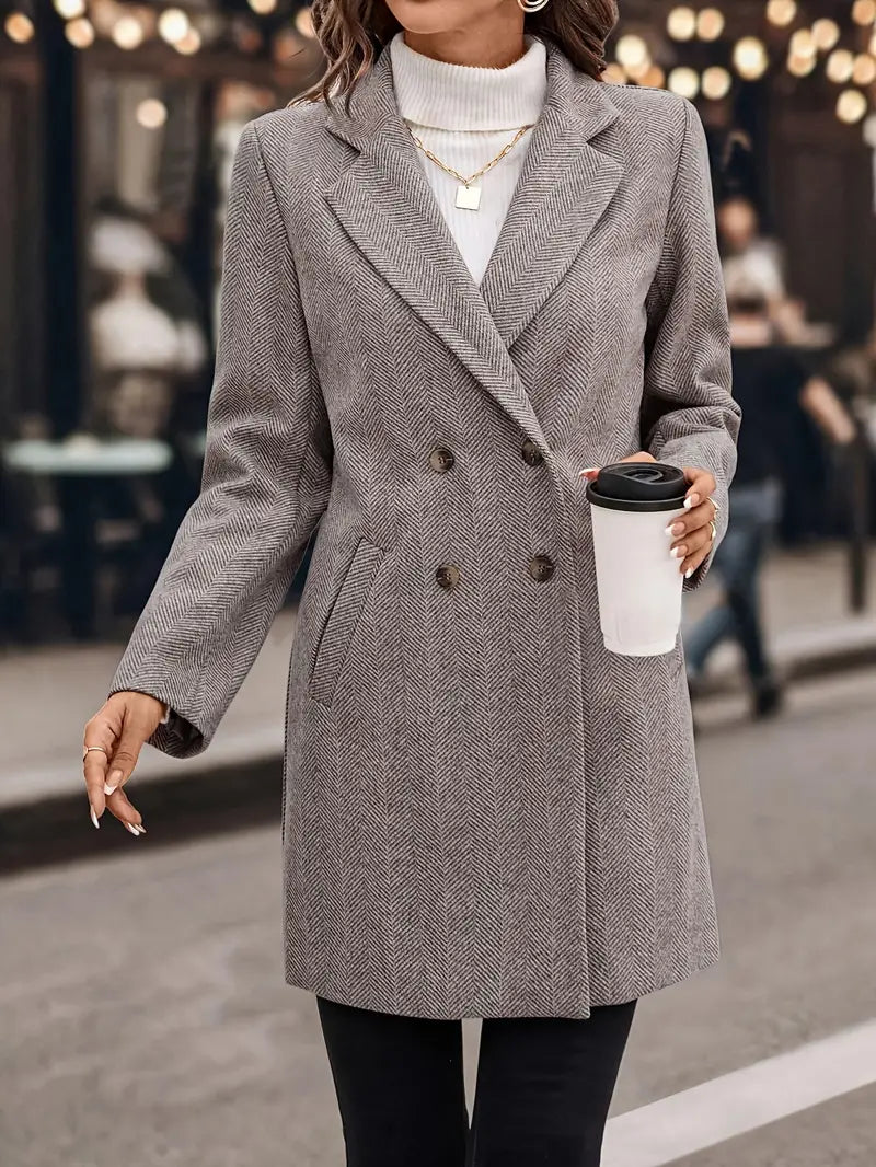Femme en manteau gris à chevrons, col roulé blanc, tenant un gobelet à café. Mode automne, élégance urbaine, style chic décontracté.