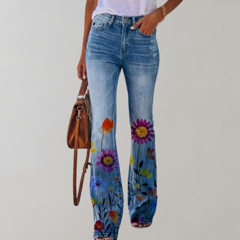 Jean femme bleu avec motifs floraux colorés, style bohème, porté avec un t-shirt blanc et un sac marron. Mode tendance, casual chic.