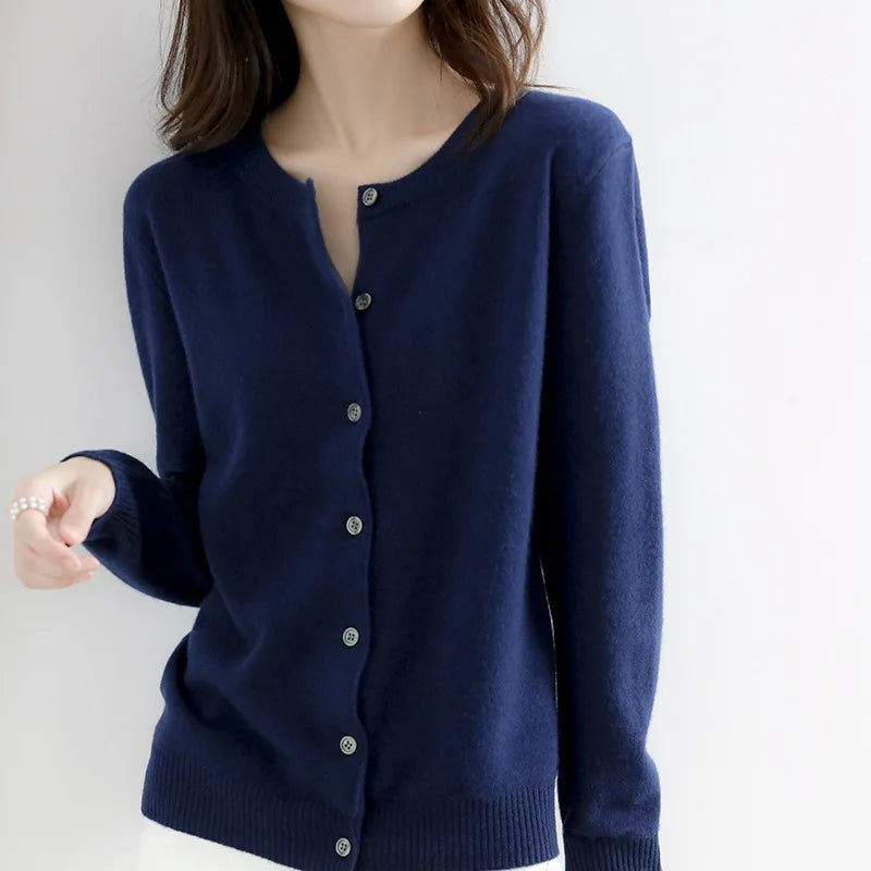 Femme portant un cardigan bleu marine en laine, manches longues, boutons argentés, style élégant et décontracté, mode automne-hiver.