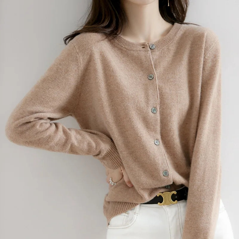 Femme portant un cardigan beige en cachemire avec boutons, associé à un jean blanc. Mode élégante, tenue automne-hiver, style décontracté chic.