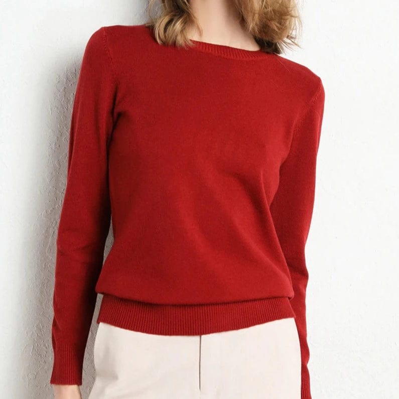 Pull rouge femme en laine, manches longues, col rond, porté avec un pantalon beige. Mode automne-hiver, style élégant et décontracté.