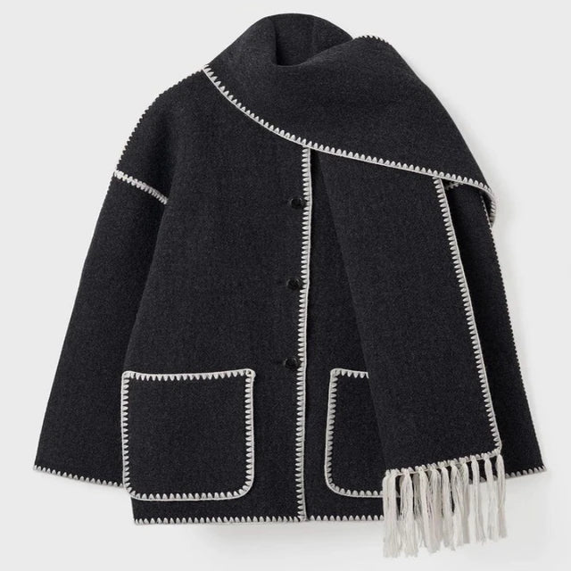 Manteau en laine noir avec bordures blanches, poches plaquées et écharpe intégrée à franges. Style élégant et moderne pour l'hiver.