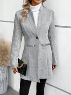 Femme portant un manteau gris à rayures, col roulé blanc, tenant un sac noir. Mode élégante, tenue automne-hiver, style chic et moderne.