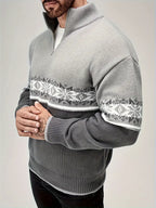 Homme portant un pull gris à col zippé avec motif nordique blanc et gris, manches longues, style hiver, mode masculine élégante.