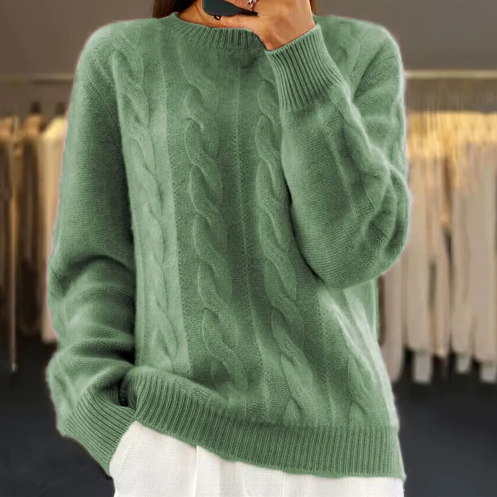 Pull vert en laine torsadée, manches longues, porté par une personne. Confortable et élégant, idéal pour l'automne et l'hiver. Mode féminine tendance.