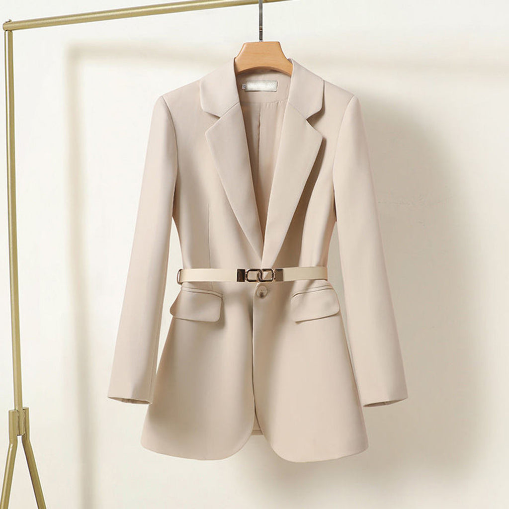 Blazer beige élégant pour femme avec ceinture, suspendu sur un cintre. Veste moderne, mode féminine, tenue professionnelle chic.