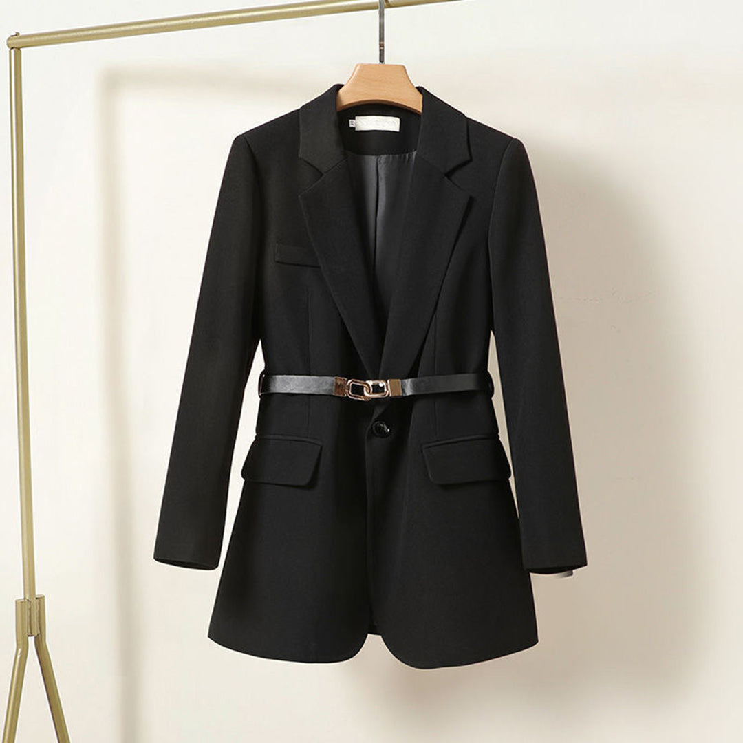 Veste blazer noir élégant pour femme avec ceinture, suspendu sur un cintre doré. Mode féminine, vêtement chic, style professionnel.