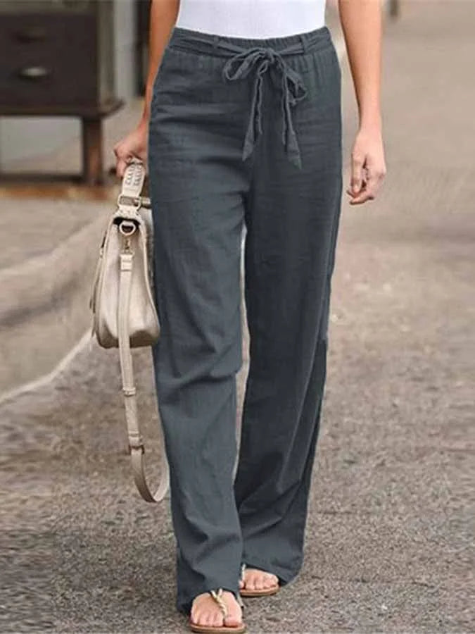 Pantalon large gris pour femme, style décontracté, avec cordon de serrage, porté avec un débardeur blanc et des sandales, sac à main beige.