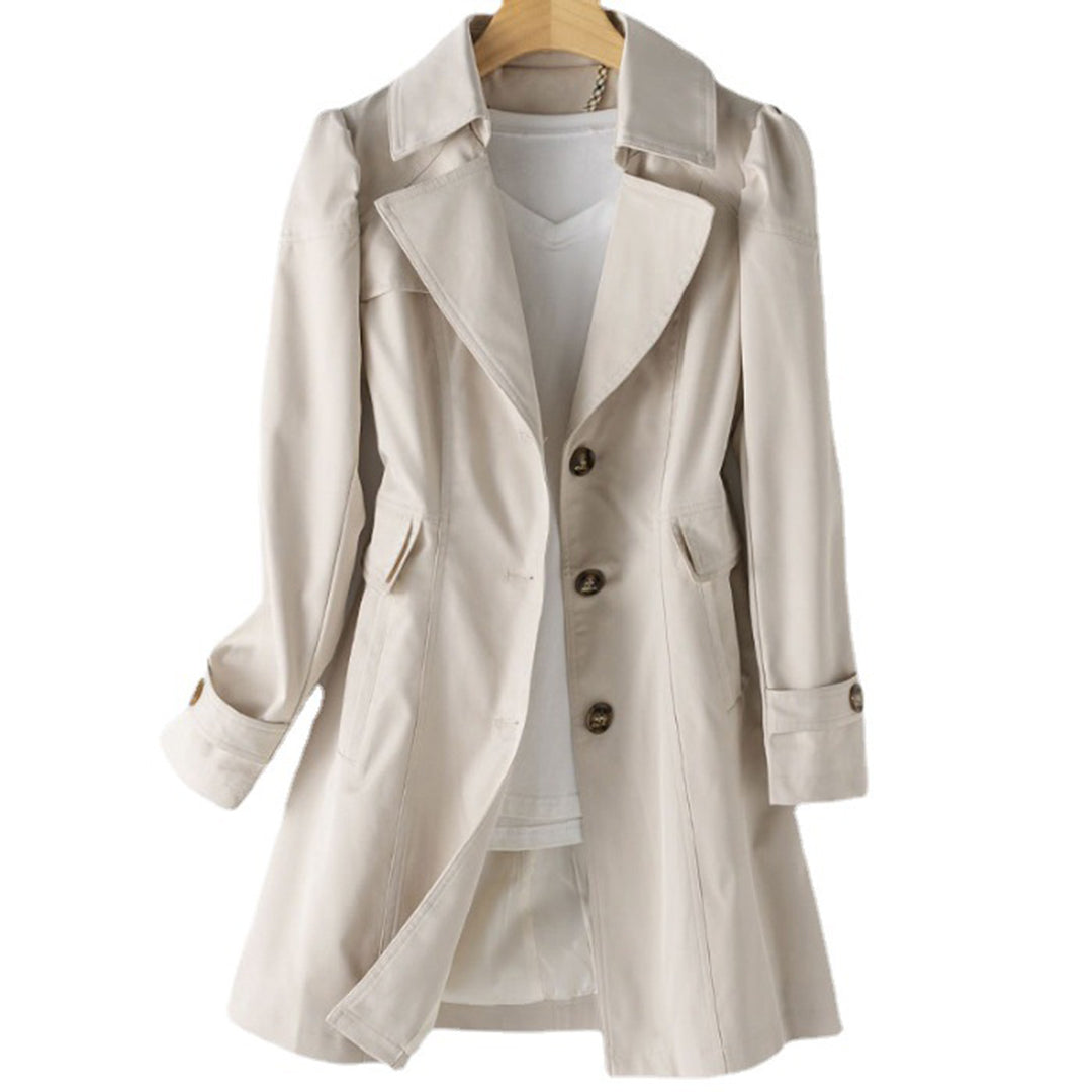 Manteau trench beige élégant pour femme, avec col large et boutons, suspendu sur un cintre en bois. Mode automne, vêtement chic et intemporel.