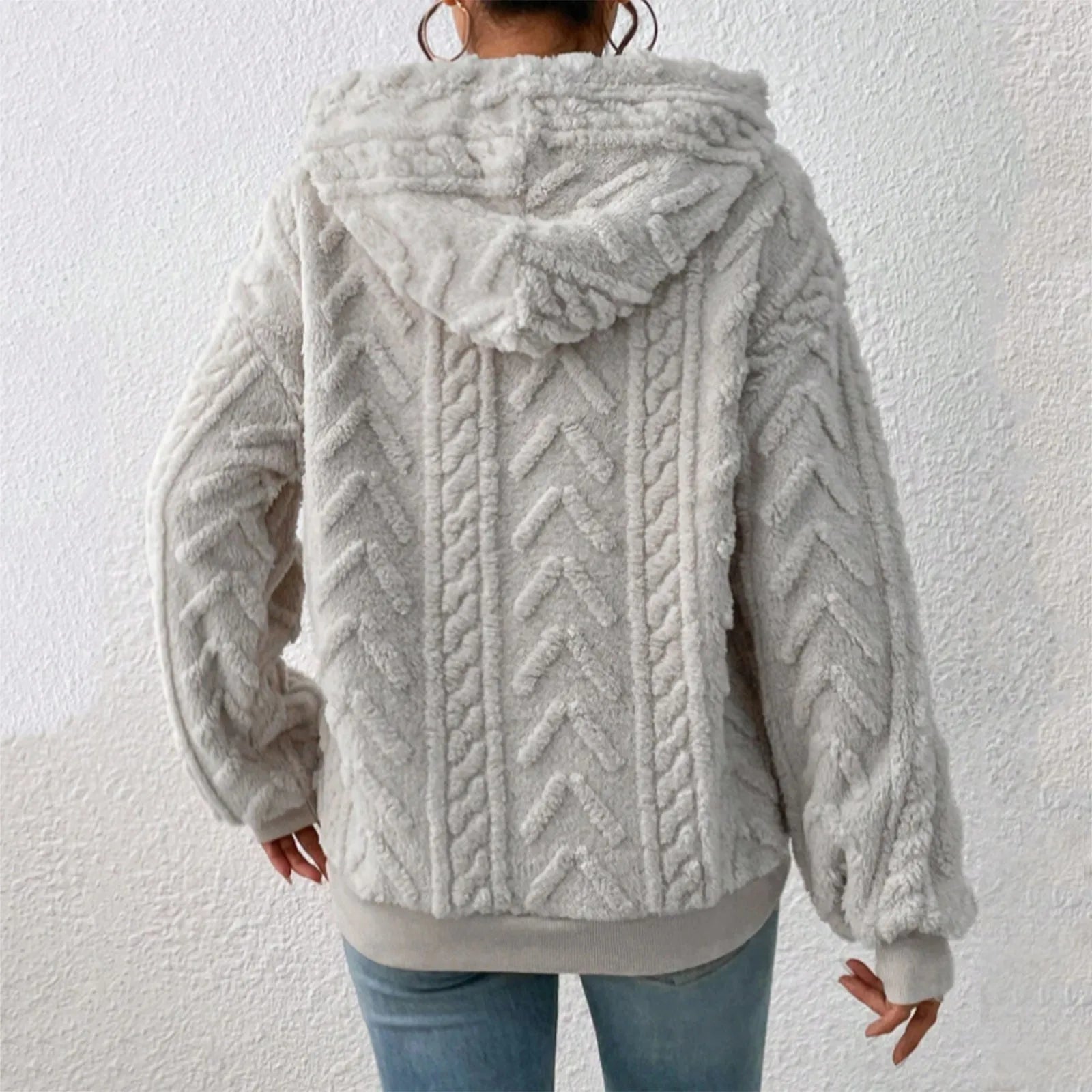Veste en fausse fourrure grise avec capuche, motif chevrons, portée par une personne de dos, style décontracté, tendance automne-hiver.