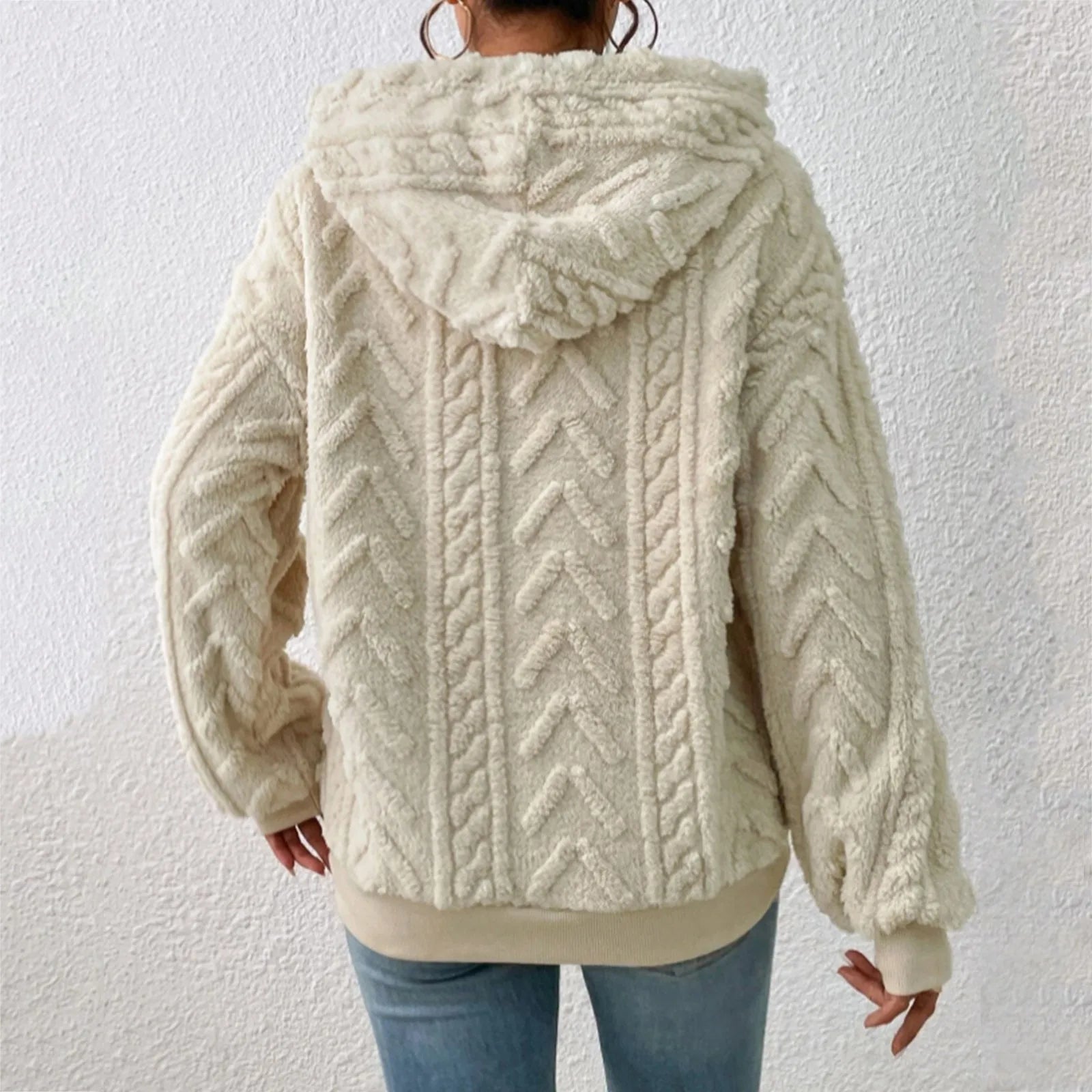 Veste en laine beige à capuche, motif torsadé, portée par une personne de dos, sur fond blanc. Mode hiver, style décontracté, tendance.