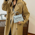 Femme en trench-coat beige tenant un sac à main bleu clair élégant, mode automne, accessoires tendance, style chic et moderne.